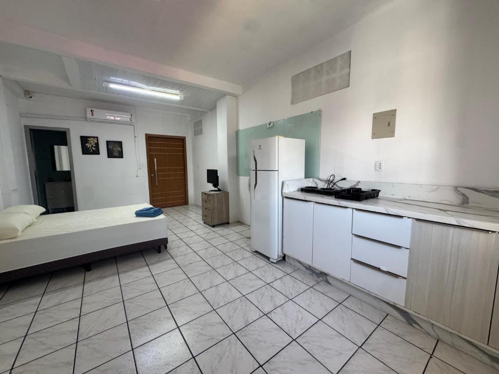 een keuken met een bed en een koelkast in een kamer bij Estudio prático e acolhedor , sua base em Floripa in São José