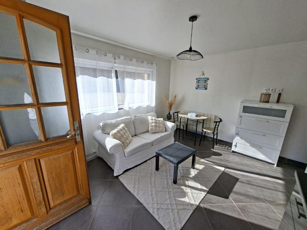 a living room with a white couch and a table at Studio Cozy in La Celle-sous-Gouzon
