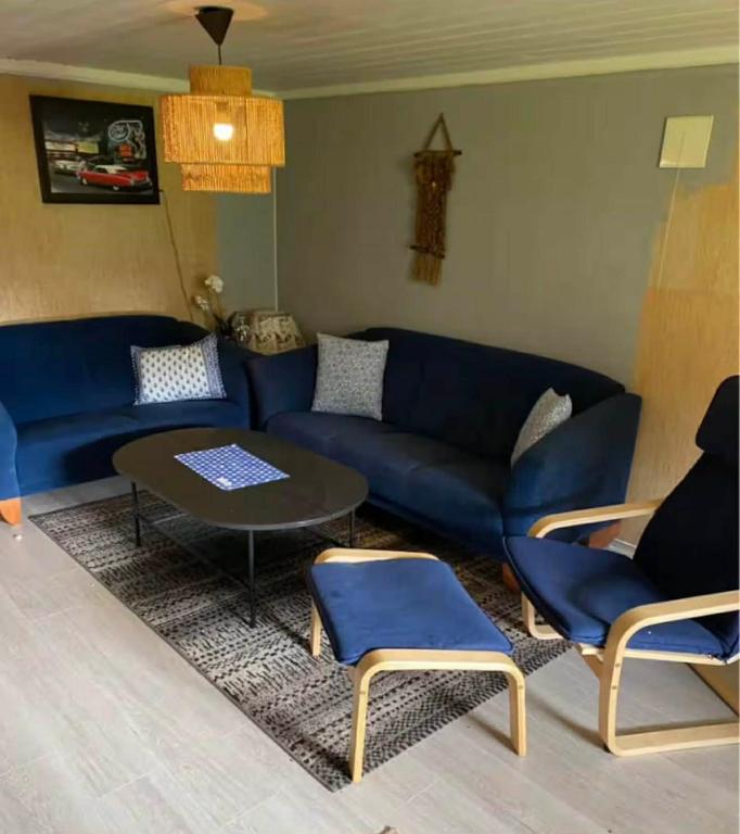 Una sala de estar con un sofá azul y sillas. en Leilighet i Damstien, 