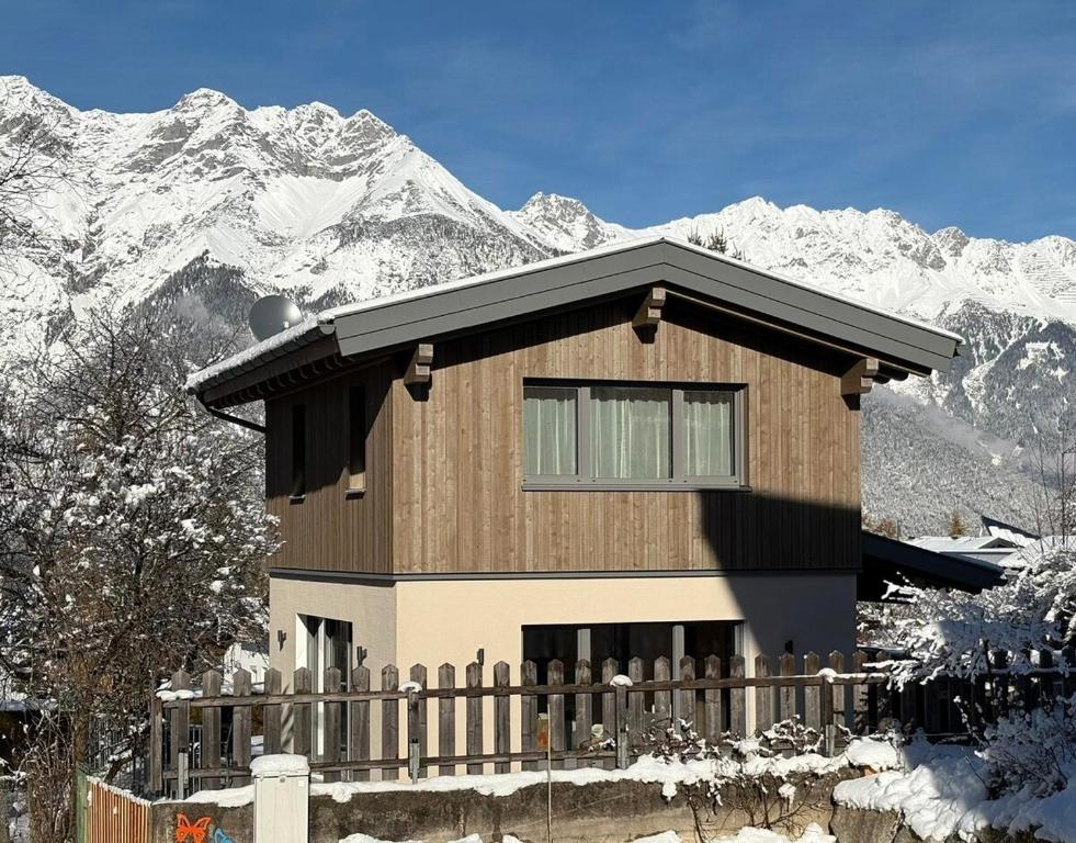 Cute House with terrace and garden في إنسبروك: منزل أمام جبل مغطى بالثلج