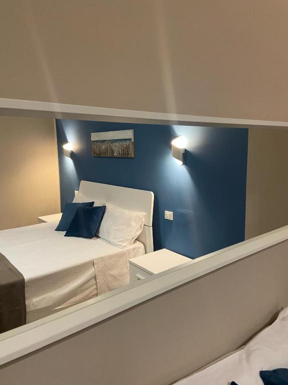 a bedroom with a blue wall with a bed and a mirror at Titti's Room in Casteldaccia