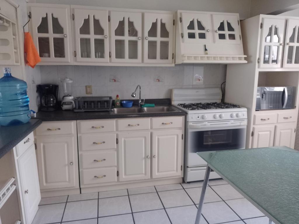 a kitchen with white cabinets and a sink and a stove at Amplía casa en Jardines Alcalde in Guadalajara