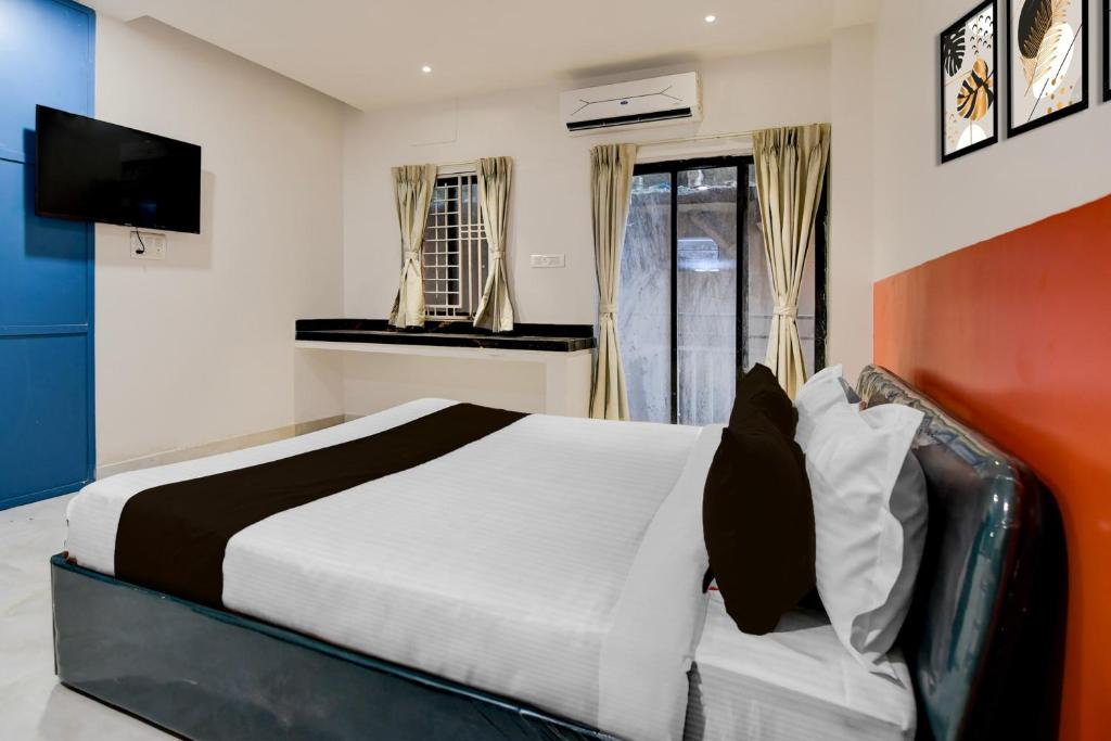 Un dormitorio con una cama grande y un televisor. en Super Hotel O Avigna Premium, en Bhubaneshwar