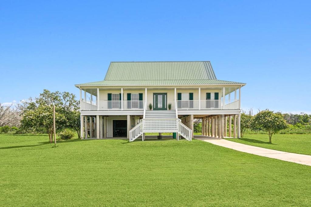 ein großes Haus mit Gründach auf einem Rasenfeld in der Unterkunft Waterfront Getaway • Balcony + Bayou Views in Lafitte
