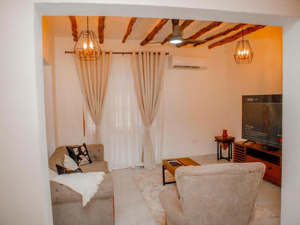 a living room with a couch and a tv at Manzi Hub Residence in Zanzibar City