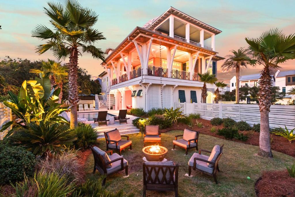 a large white house with chairs in a yard at Pomp in Paradise in Inlet Beach