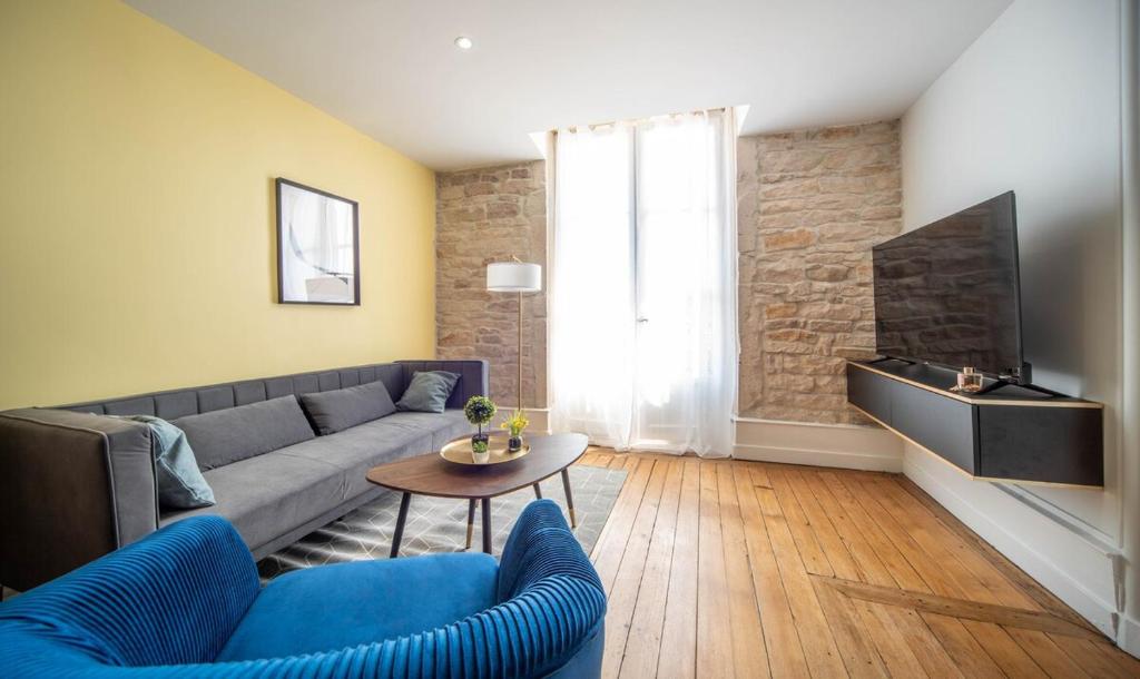 a living room with a couch and a tv at Place Carnot in Tournus