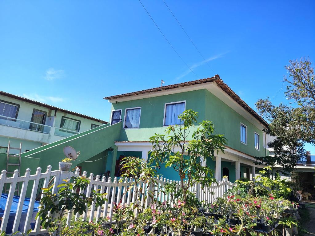 una casa verde e bianca con una recinzione bianca di Casa Verde ad Arraial do Cabo