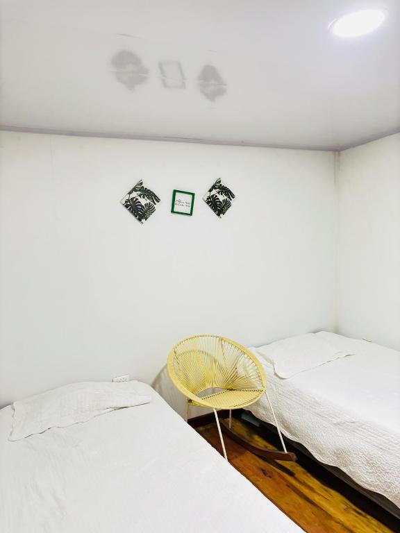 a bedroom with two beds and a yellow chair at Casa finca platanales in Cartagena de Indias