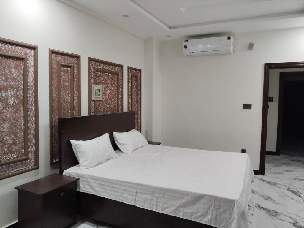 a bedroom with a white bed with a wooden headboard at Royal Apartments-One Bed Apartments in Islamabad