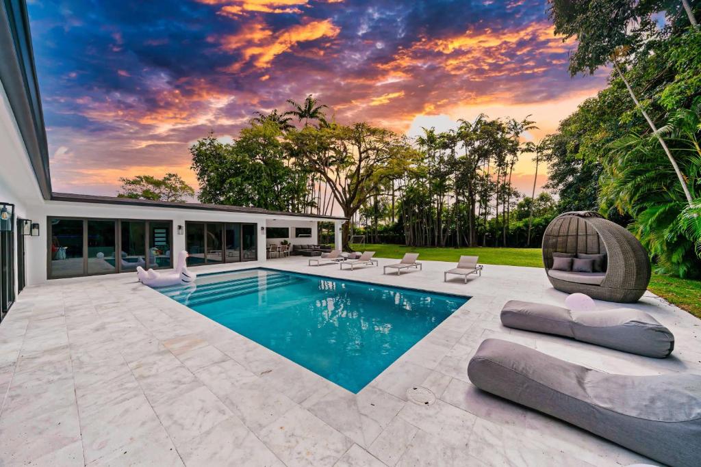 Una piscina en un patio trasero con una puesta de sol. en Two Neighboring Villas in The Heart of Miami, en Golden Glades