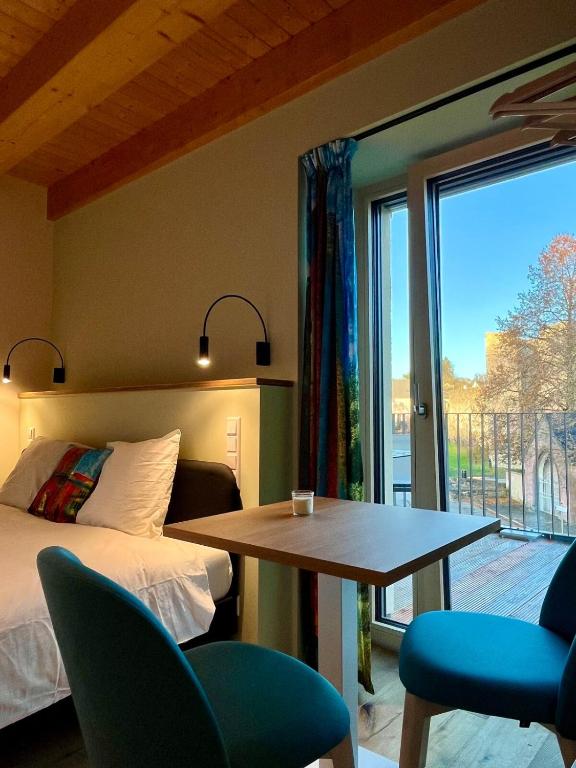 una camera da letto con un letto, un tavolo e una finestra di Gîte Koerich a Koerich