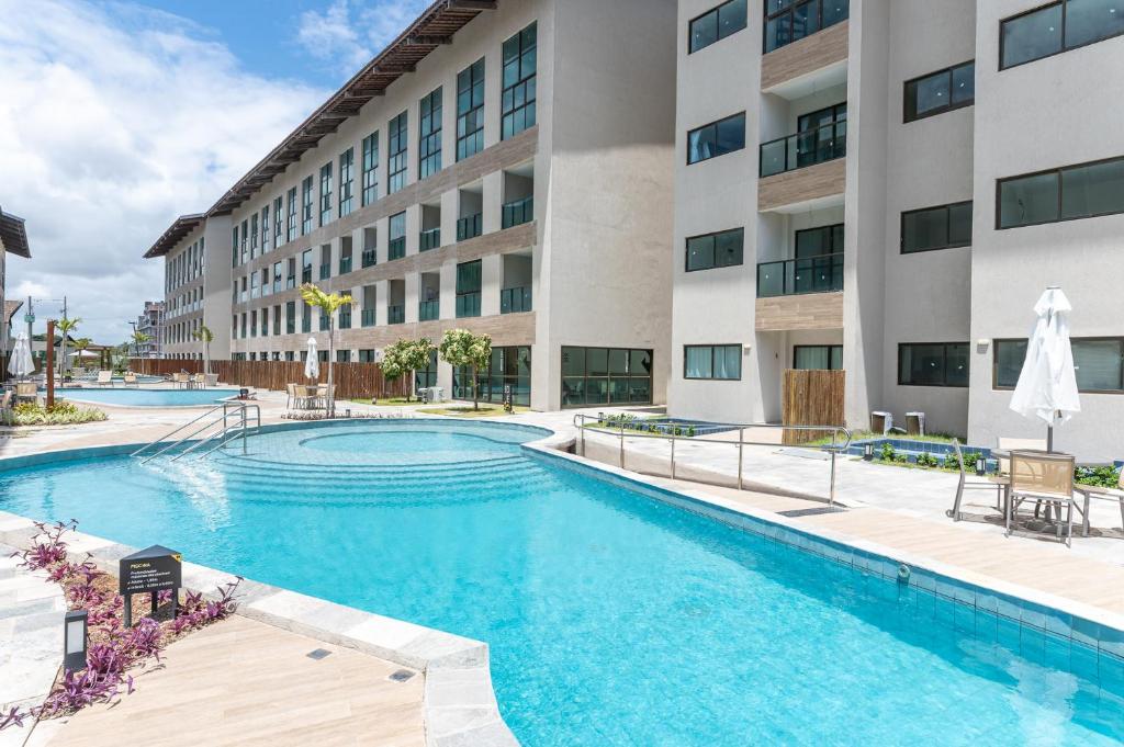 an image of a swimming pool in front of a building at Max Carneiros Suítes - Conforto e sofisticação há alguns passos do mar! in Tamandaré
