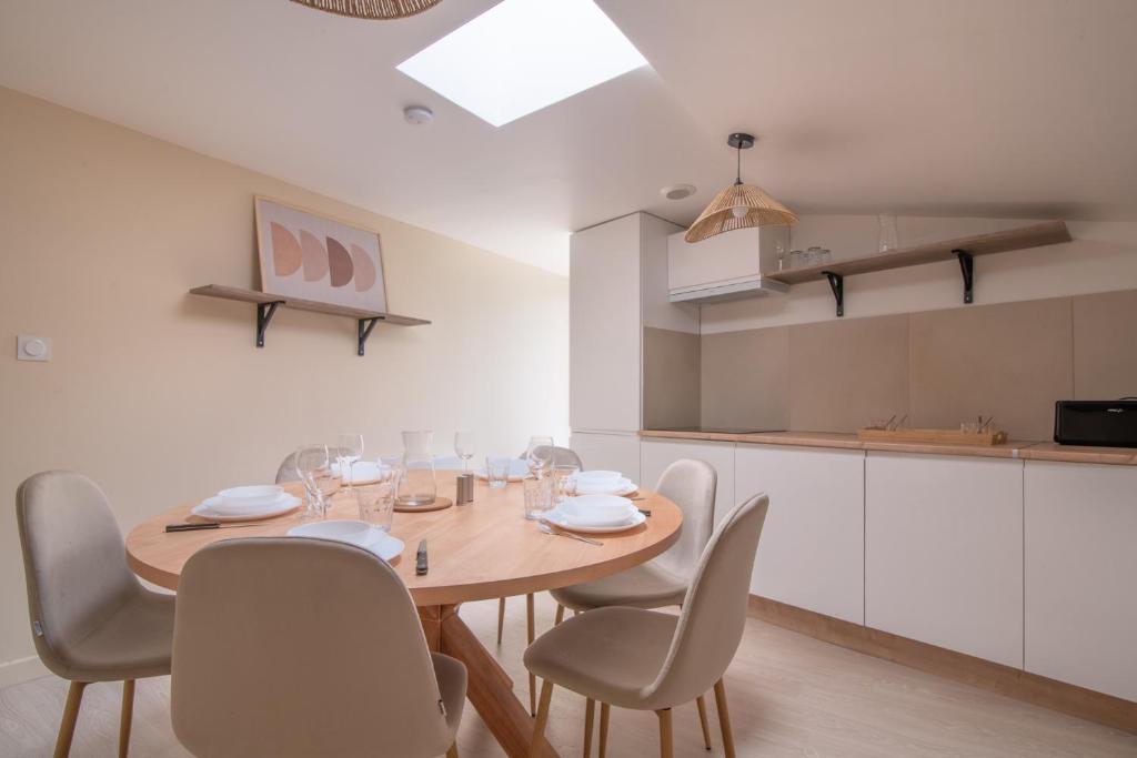 ein Esszimmer mit Tisch und Stühlen und eine Küche in der Unterkunft La Parenthèse - Proche Puy du Fo u - 2 appartements équipés et confortables au coeur des Herbiers in Les Herbiers