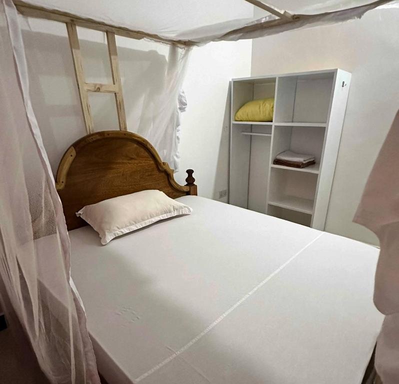 een bed met een houten hoofdeinde in een kamer bij Кокосовый домик in Nungwi