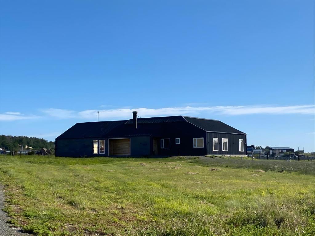 a black house in the middle of a field at Casa Cálida entorno natural con vista al Estrecho in Leñadura