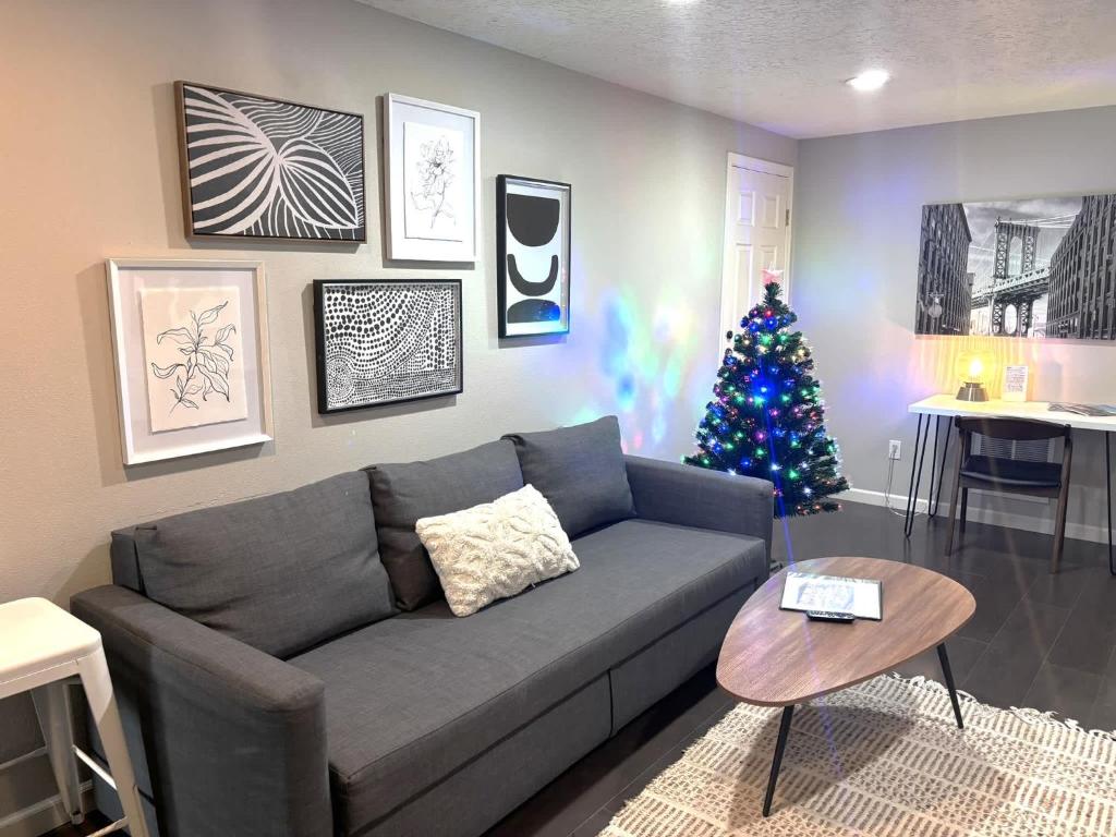 #StayInMyDistrict Piedmont Near Parks and Shopping في بورتلاند: غرفة معيشة مع أريكة رمادية وشجرة عيد الميلاد