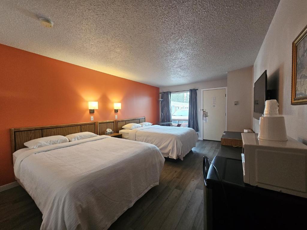 2 letti in una camera d'albergo con pareti arancioni di Howard Johnson by Wyndham Edson a Edson