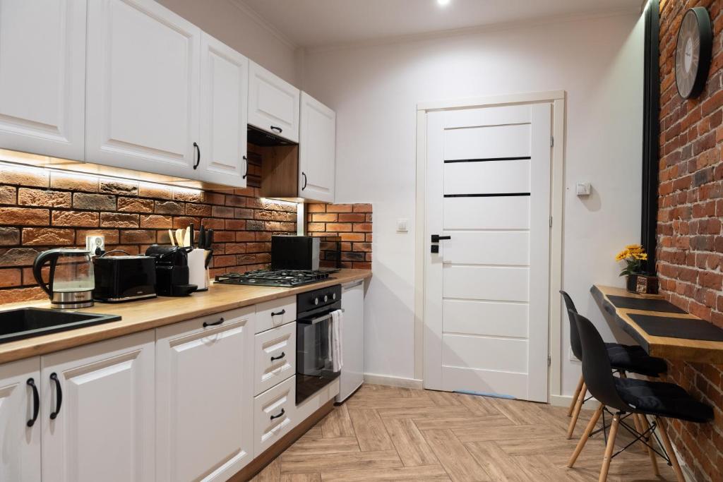 a kitchen with white cabinets and a brick wall at Lusia Apartment in Jarosław