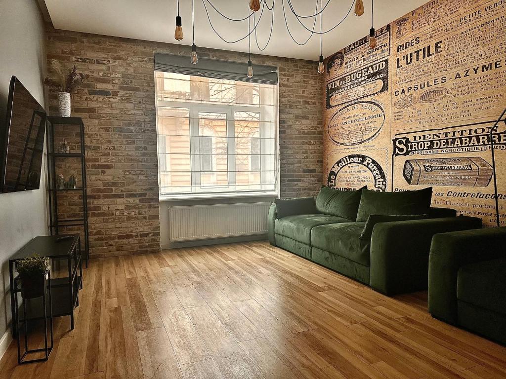 a living room with a green couch and a brick wall at Kobylianska-Premium 2 Room in Chernivtsi