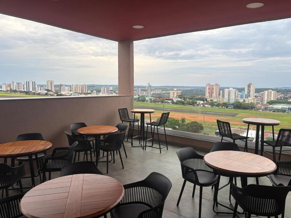 a restaurant with tables and chairs and a view of the city at Red Building Apartment in Bauru