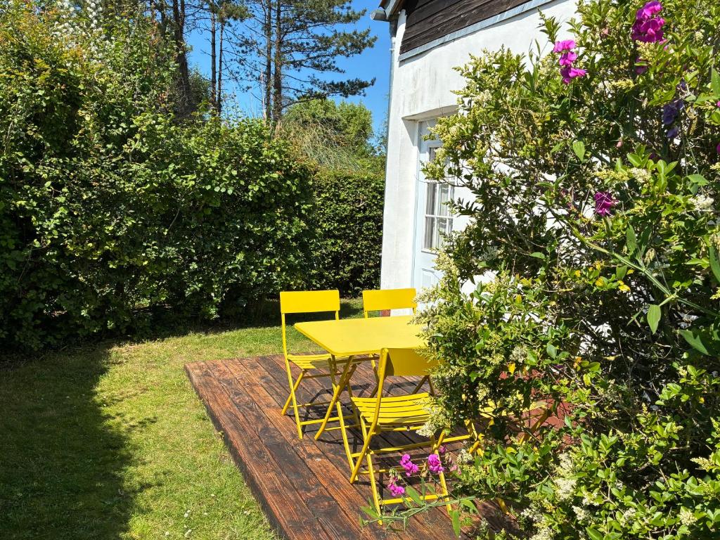 un tavolo giallo e delle sedie in un giardino di Maison de campagne au bord de la mer a Fort-Mahon-Plage