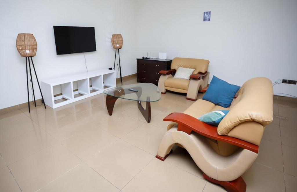 un soggiorno con 2 sedie e una TV di Ocean Heights - One Bedroom a Accra