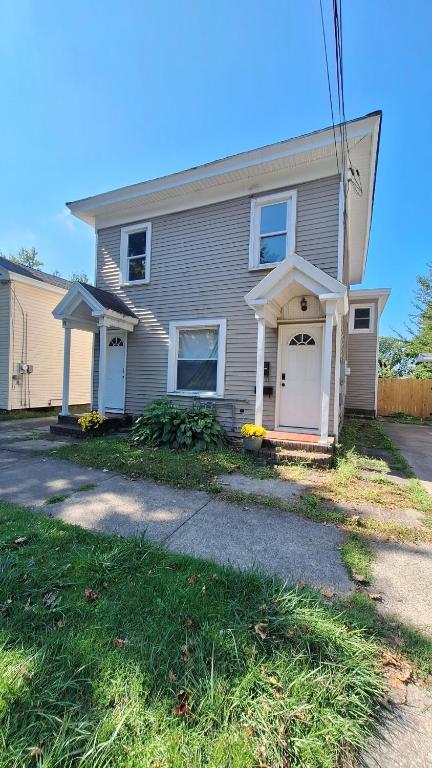 a gray house with white doors and a driveway at Oswego 3BR Apt close to SUNY, Downtown & Lake Ontario in Oswego