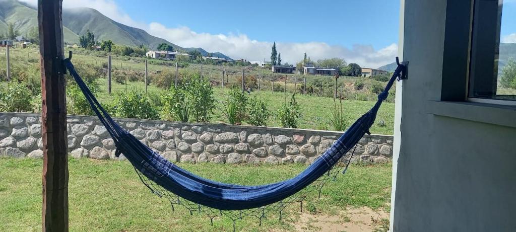 een blauwe hangmat die in een raam hangt met een rotswand bij Al Paraíso in Tafí del Valle