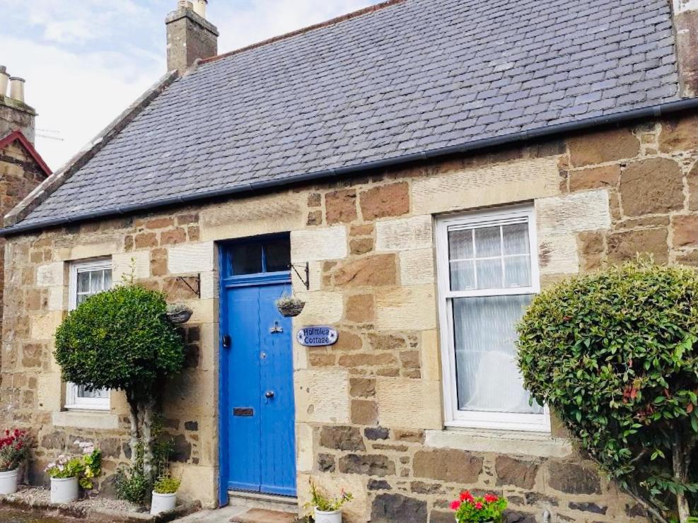 a stone house with a blue door at Holmlea Cottage in Freuchie
