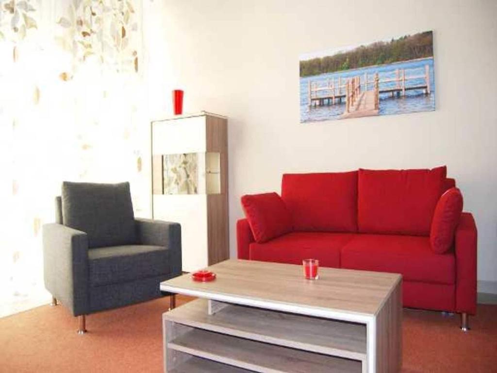 a living room with a red couch and a chair at Apartment für den perfekten Urlaub in Granzow