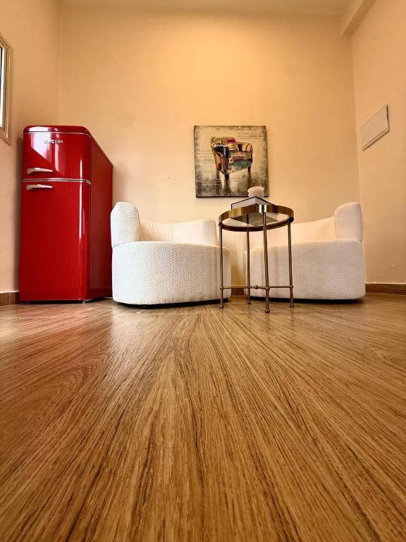 Una habitación con un refrigerador rojo y dos sillas blancas. en Irooms770, en Haifa