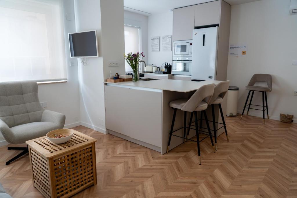 a kitchen with white cabinets and a kitchen island with stools at Luxury Gran Vía centro Murcia in Murcia