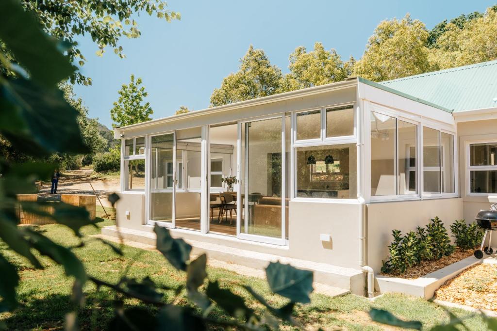 a large white house with large windows at Patryssenvalleij Farm and Cottages in Stellenbosch