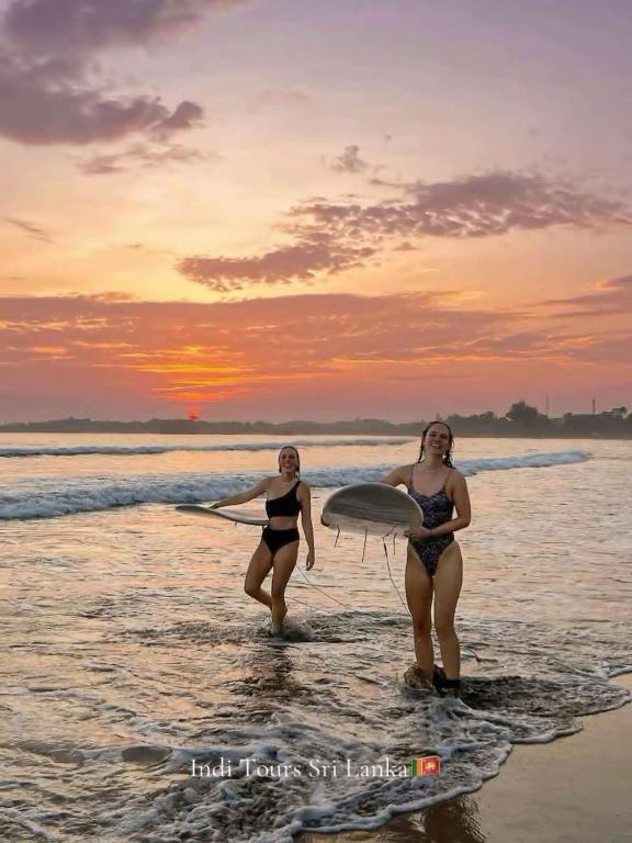 two women walking in the water on the beach at Imaa freedom house in Nilwella