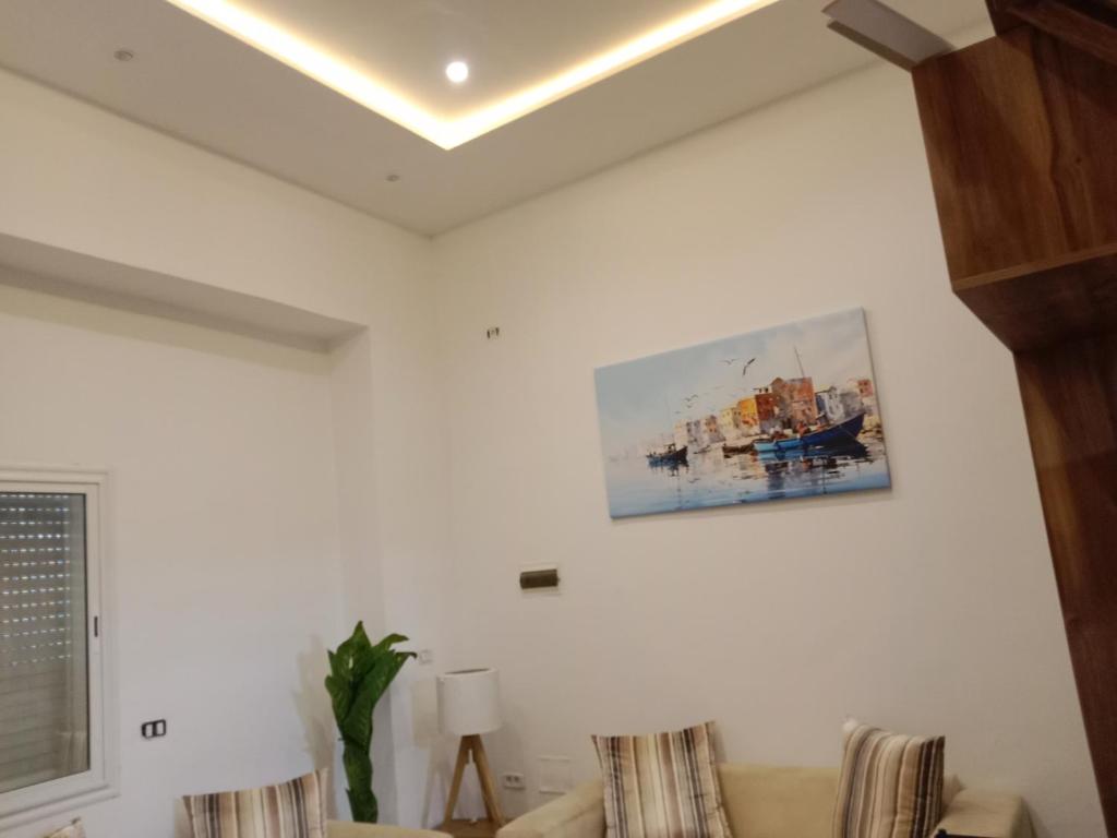a living room with a couch and a painting on the wall at Front beach cosy apartment in La Goulette