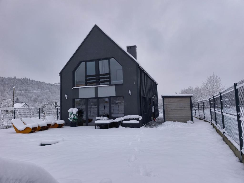 ein schwarzes Haus mit Schnee auf dem Boden davor in der Unterkunft Stodoła pod Bacówką Zawoja Sauna Jacuzzi in Skawica