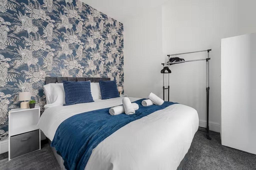 a bedroom with a bed with blue and white wallpaper at Modern 4BR Parking in Manchester