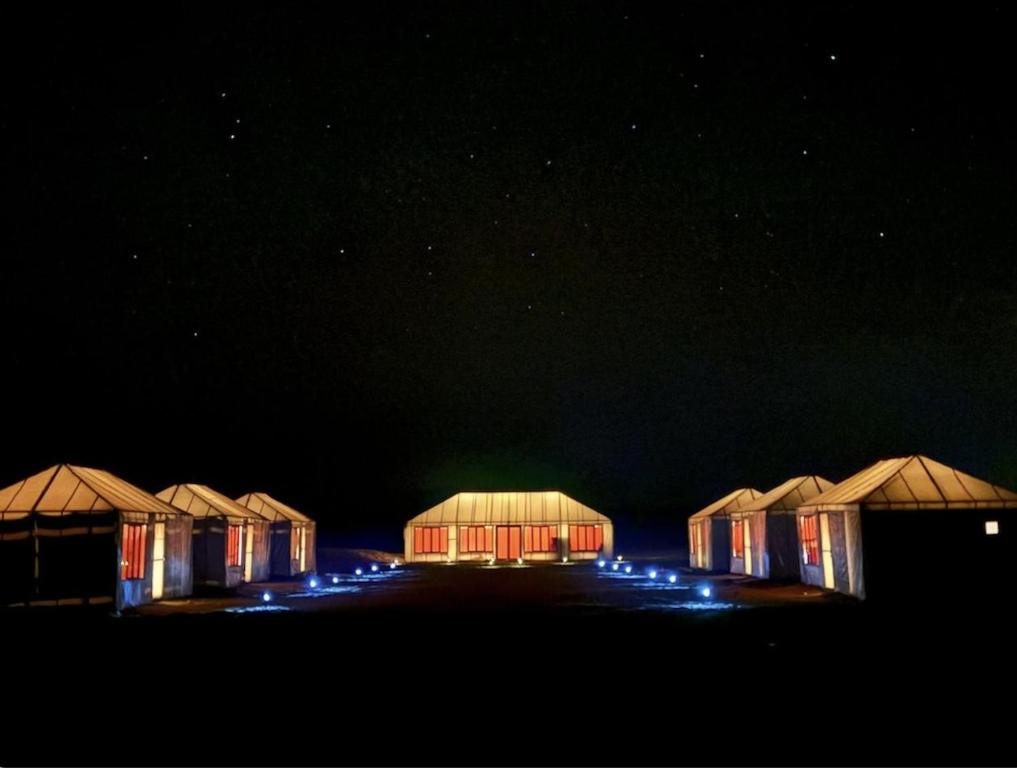 eine Reihe von Hütten, die nachts beleuchtet sind in der Unterkunft Arawan Luxury Desert Camp at Erg Lihoudi in Mhamid