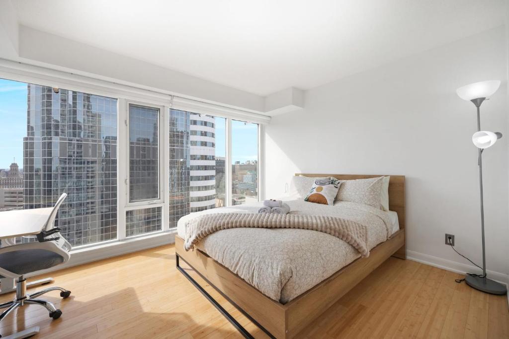 a bedroom with a bed and a desk and windows at Stunning 27th Floor Suite - Close to Eaton Centre -The Roland in Toronto