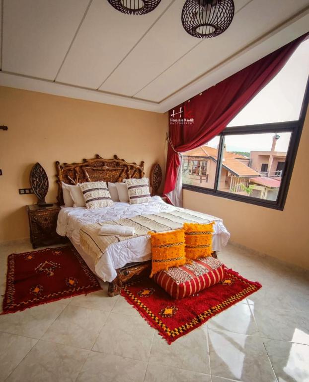 a bedroom with a large bed and a large window at Tynass Ferme - Atlas Room Fes in Douar er Rouazi