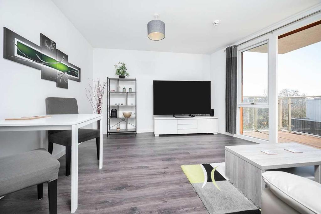 a living room with a flat screen tv and a table at Stunning 2BR flat with balcony in Maidenhead