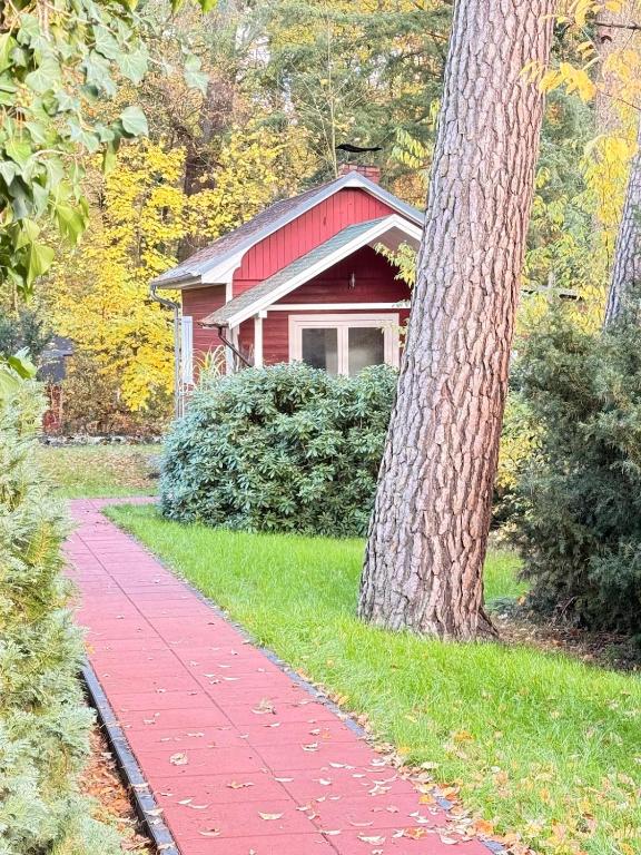a red house with a tree and a red sidewalk at Chalet im Wald mit Sauna in Schönwalde