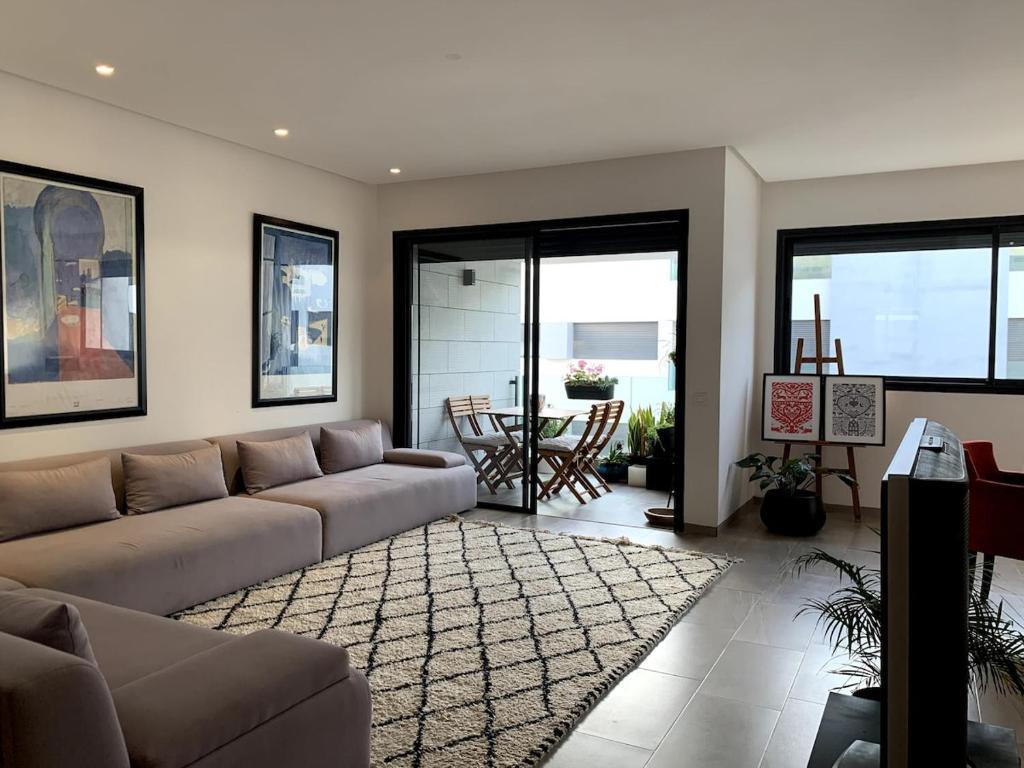 Grand Appart 3 chambres à 300 m de la Plage avec piscine et garage في تمارة: غرفة معيشة بها أريكة وطاولة