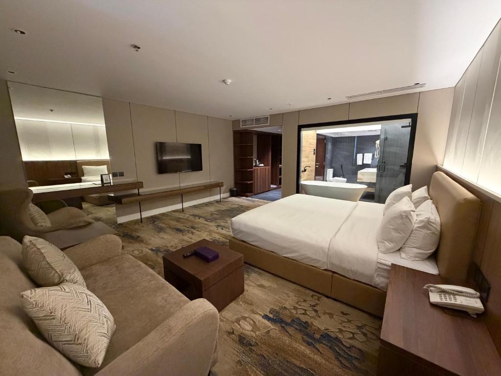ein großes Hotelzimmer mit einem Bett und einer Couch in der Unterkunft Quiet Dreams - Serviced Apartments King abdul Aziz Street Branch in Dschidda