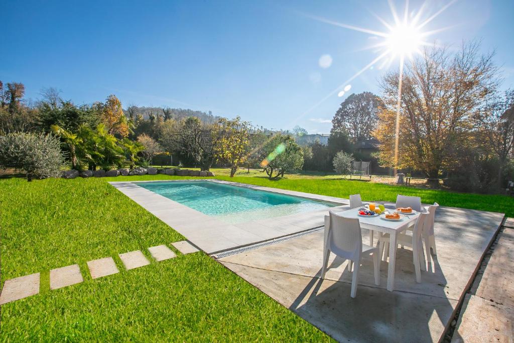 un tavolo e delle sedie accanto a una piscina di Anita Lake Fitness Retreat - Happy Rentals a Gemonio