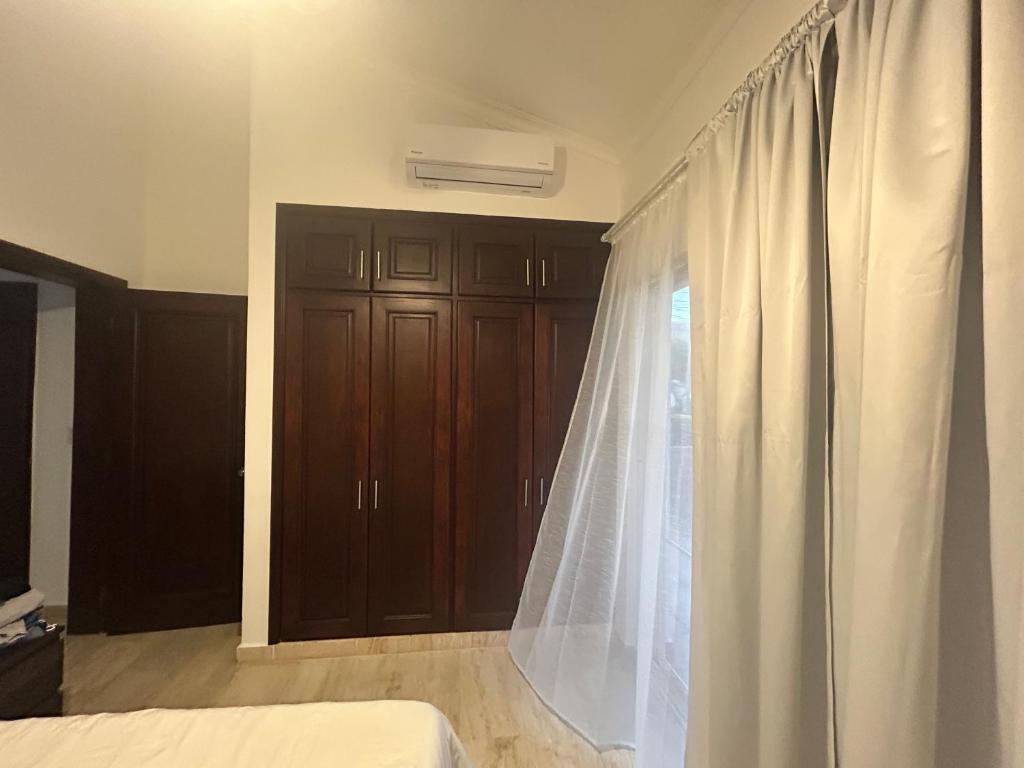 een slaapkamer met een wit gordijn en houten kasten bij Cozy apartment in Punta Cana