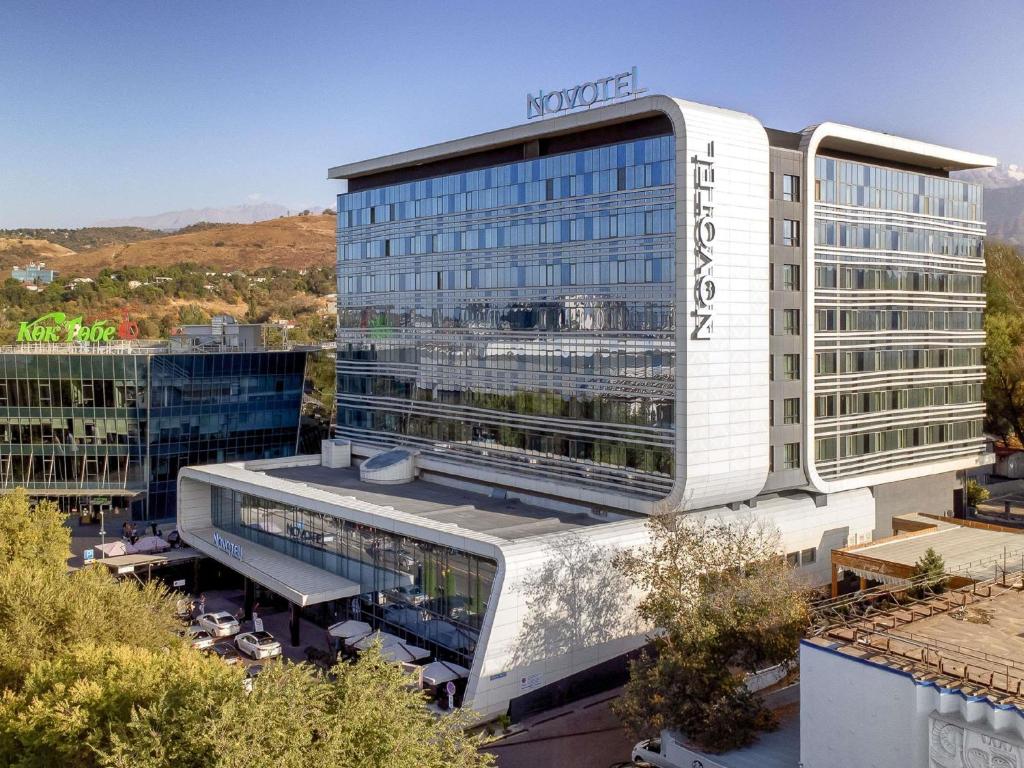 a building with a sign on top of it at Novotel Almaty City Center in Almaty