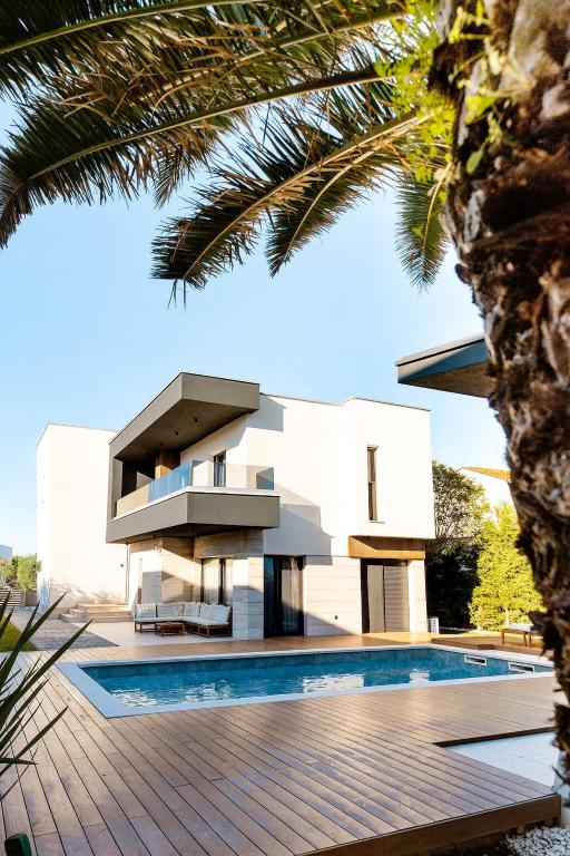 a white house with a swimming pool in front of it at Luxury Villa Positiva in Vir