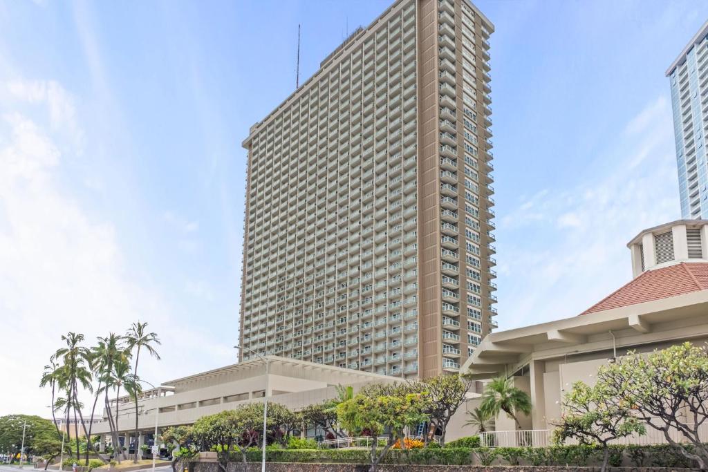 a tall building with palm trees in front of a building at Ala Moana Condo Hotel in Honolulu